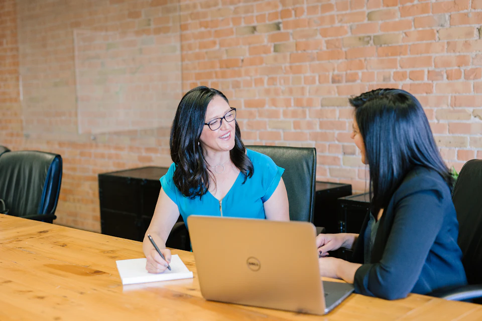 Two professionals working through figures at a laptop